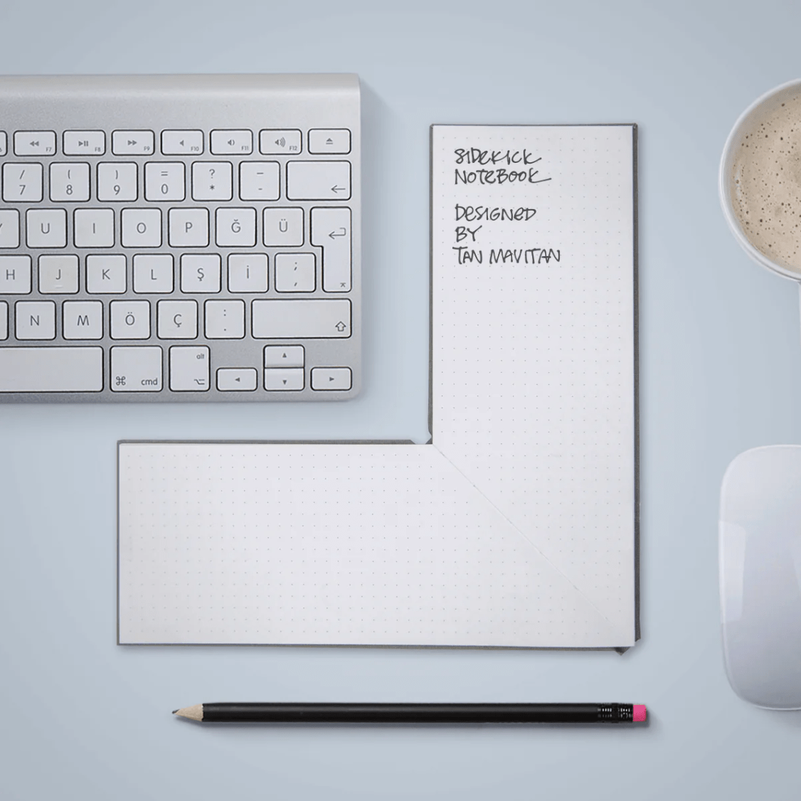 Keyboard with L-shaped notebook next to di and a pen below.